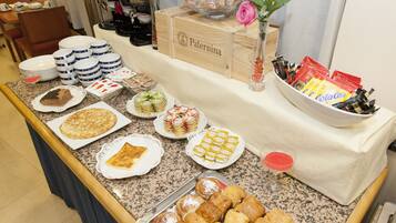 Una mesa de buffet con diversos alimentos, como pasteles, postres y bebidas.