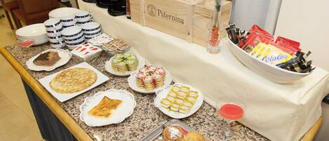 Una mesa de buffet con diversos alimentos, como pasteles, postres y bebidas.