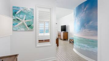 A room with a large ocean mural, a starfish artwork, and a wooden floor.