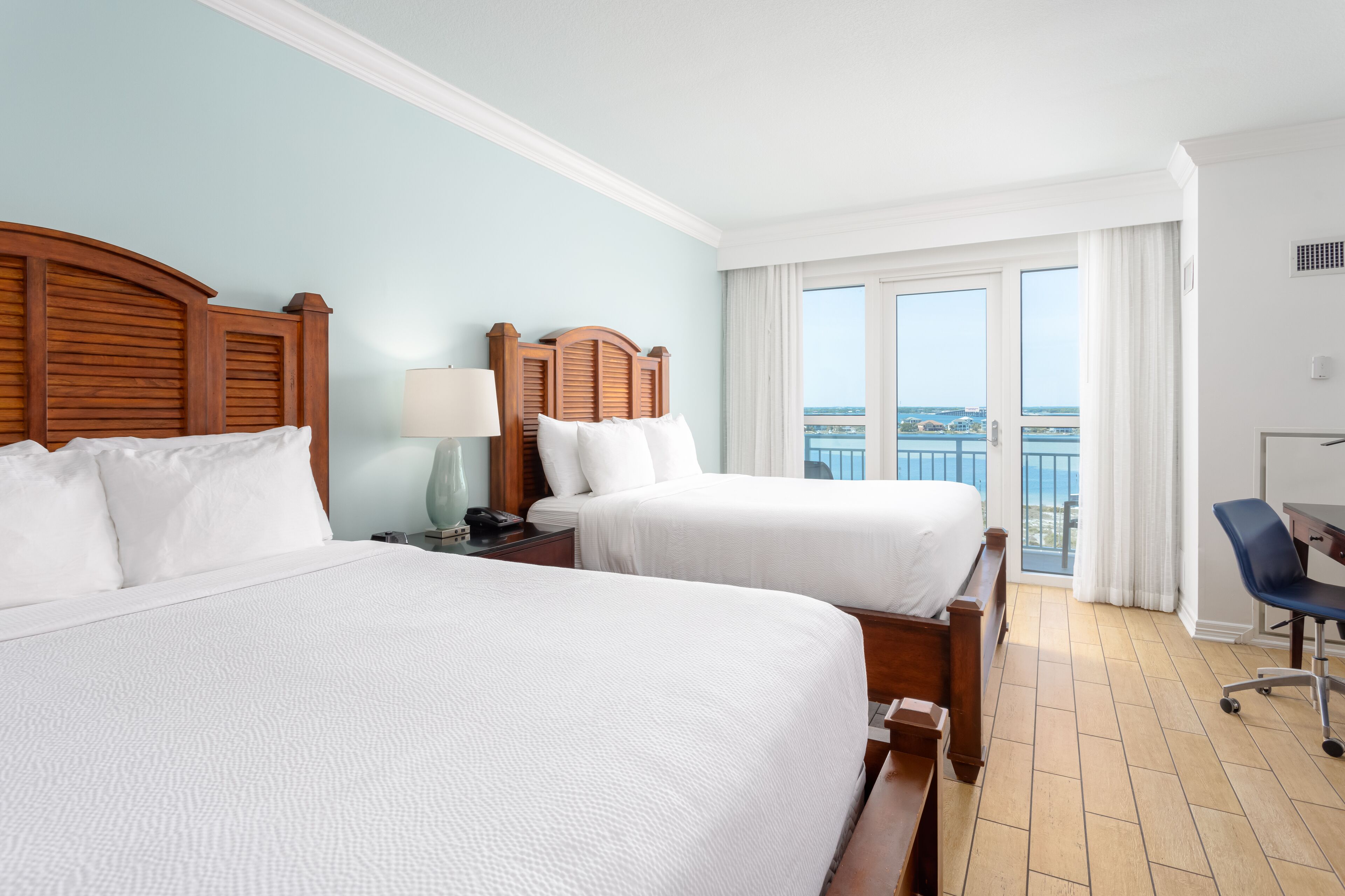 A hotel room with two beds, a desk, and a chair.