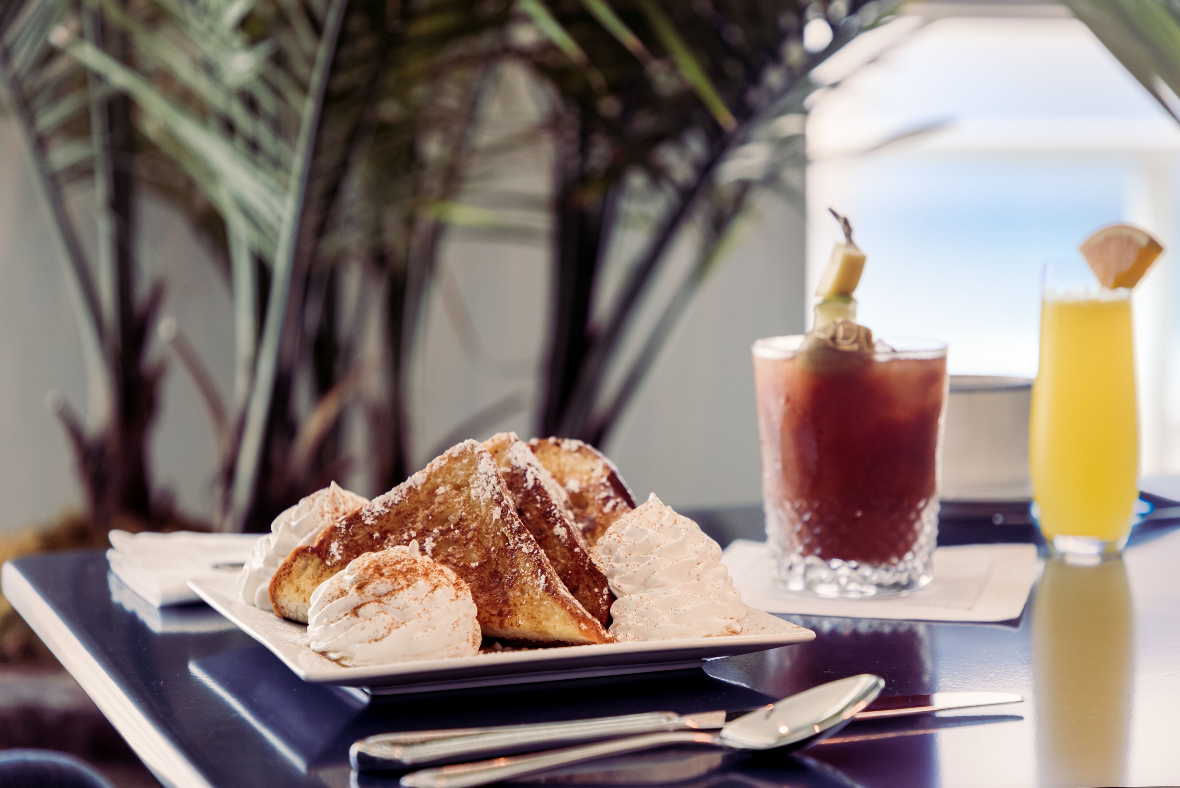 A dessert plate with a beverage and a glass of juice on a table.