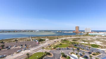 A parking lot with multiple lanes and a view of a body of water and buildings in the background.