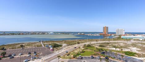 A parking lot with multiple lanes and a view of a body of water and buildings in the background.