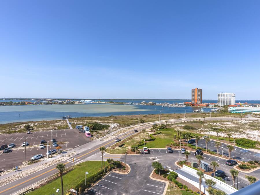 A parking lot with multiple lanes and a view of a body of water and buildings in the background.