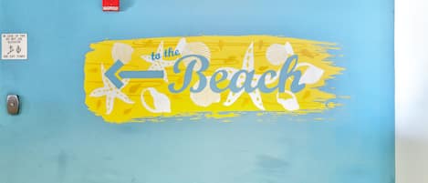 A wall with a blue and yellow design, including the text "to the Beach" and a starfish.