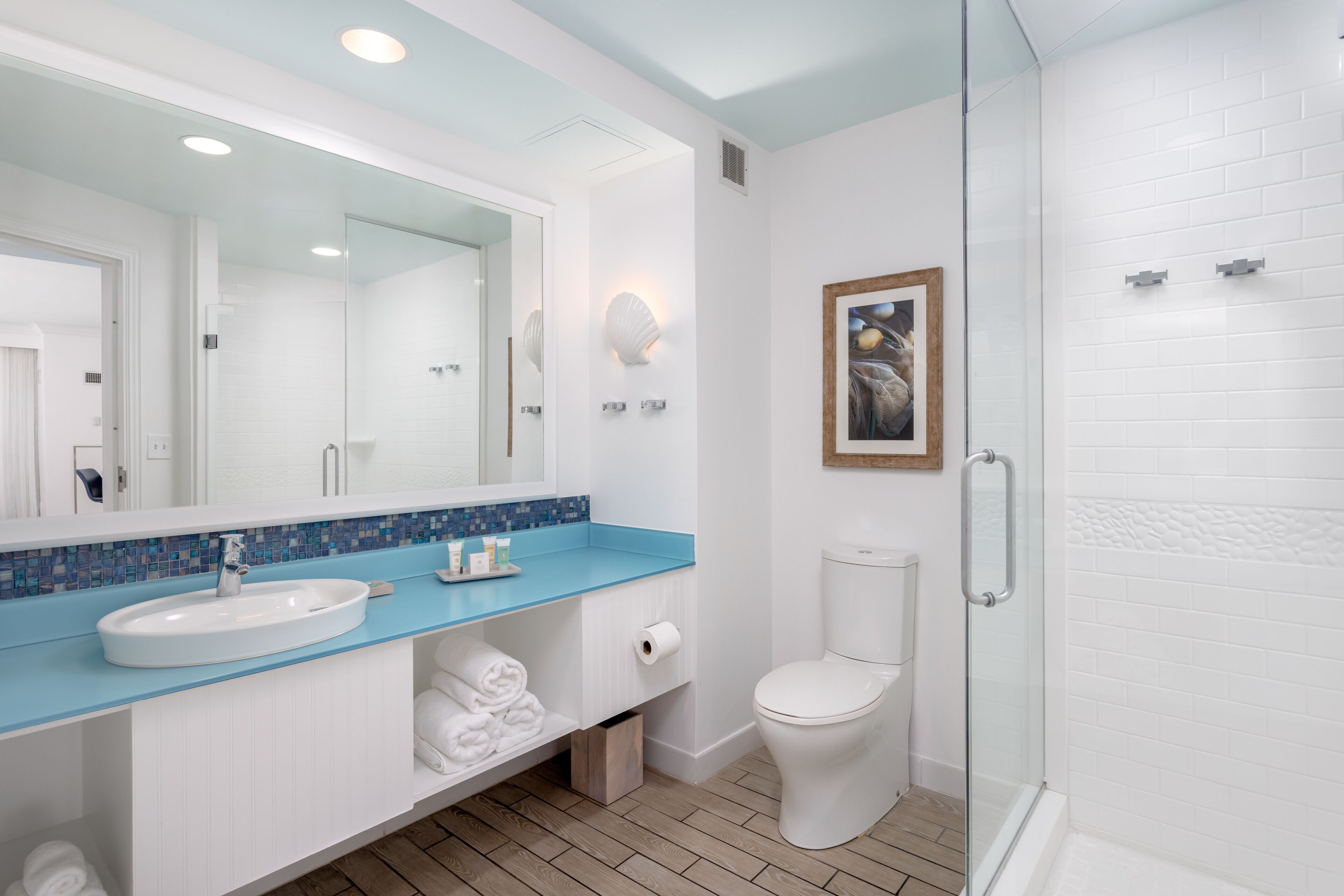 A modern bathroom with a large mirror, a sink, a toilet, and a shower area.