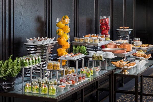 A buffet table with various food items and a decorative yellow bell pepper arrangement. - Hilton Vienna Plaza (Vienna)