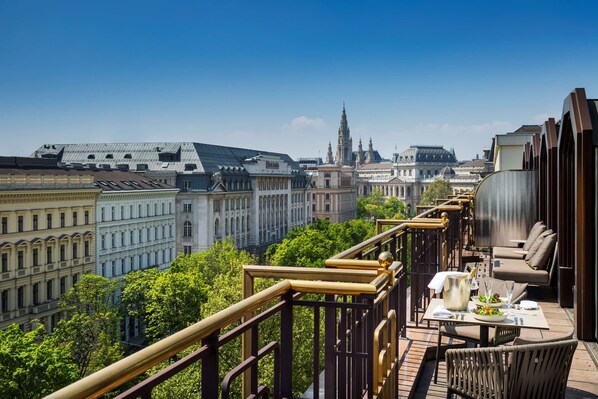 Un balcón con mesa lista para comer, con vista a un paisaje urbano con edificios históricos.