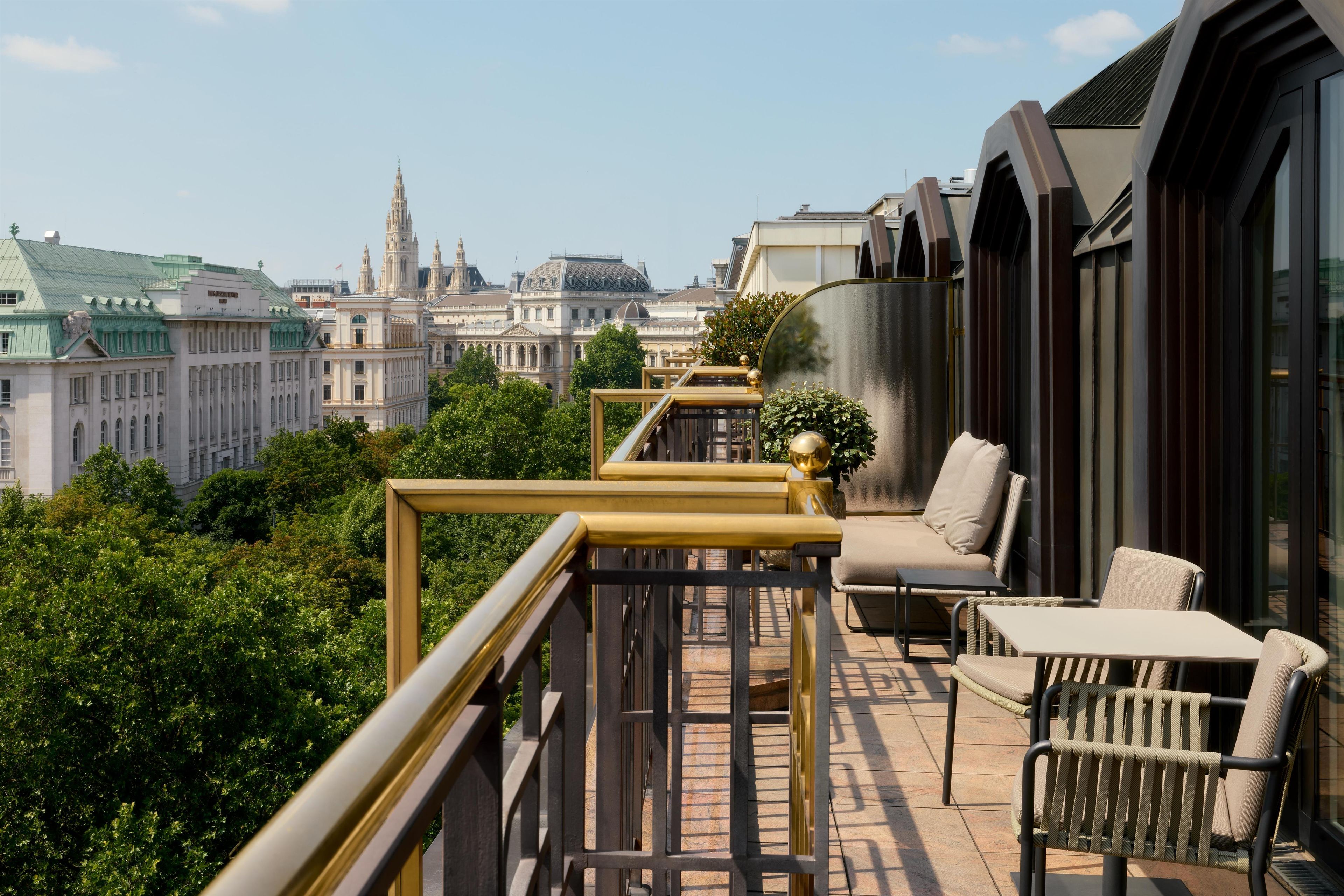 A balcony with outdoor furniture, a view of historic buildings, and a clear sky.