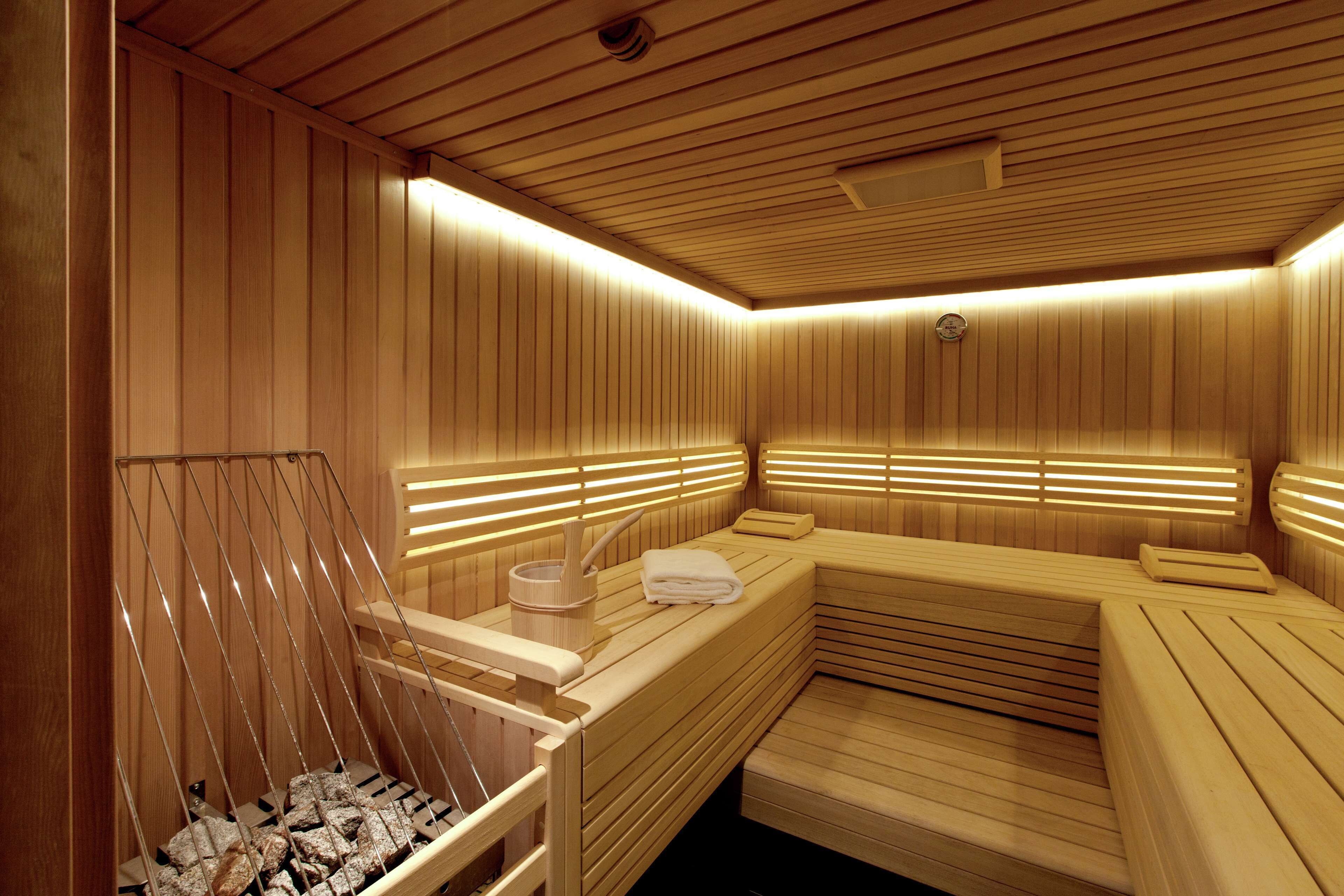 Uma sala de sauna com paredes e bancos de madeira, um banco de madeira com uma toalha, e uma bacia de pedra.