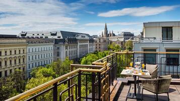 Een balkon met een ontbijtje aan tafel, met uitzicht op een stadsgezicht met historische gebouwen en een kerktoren.