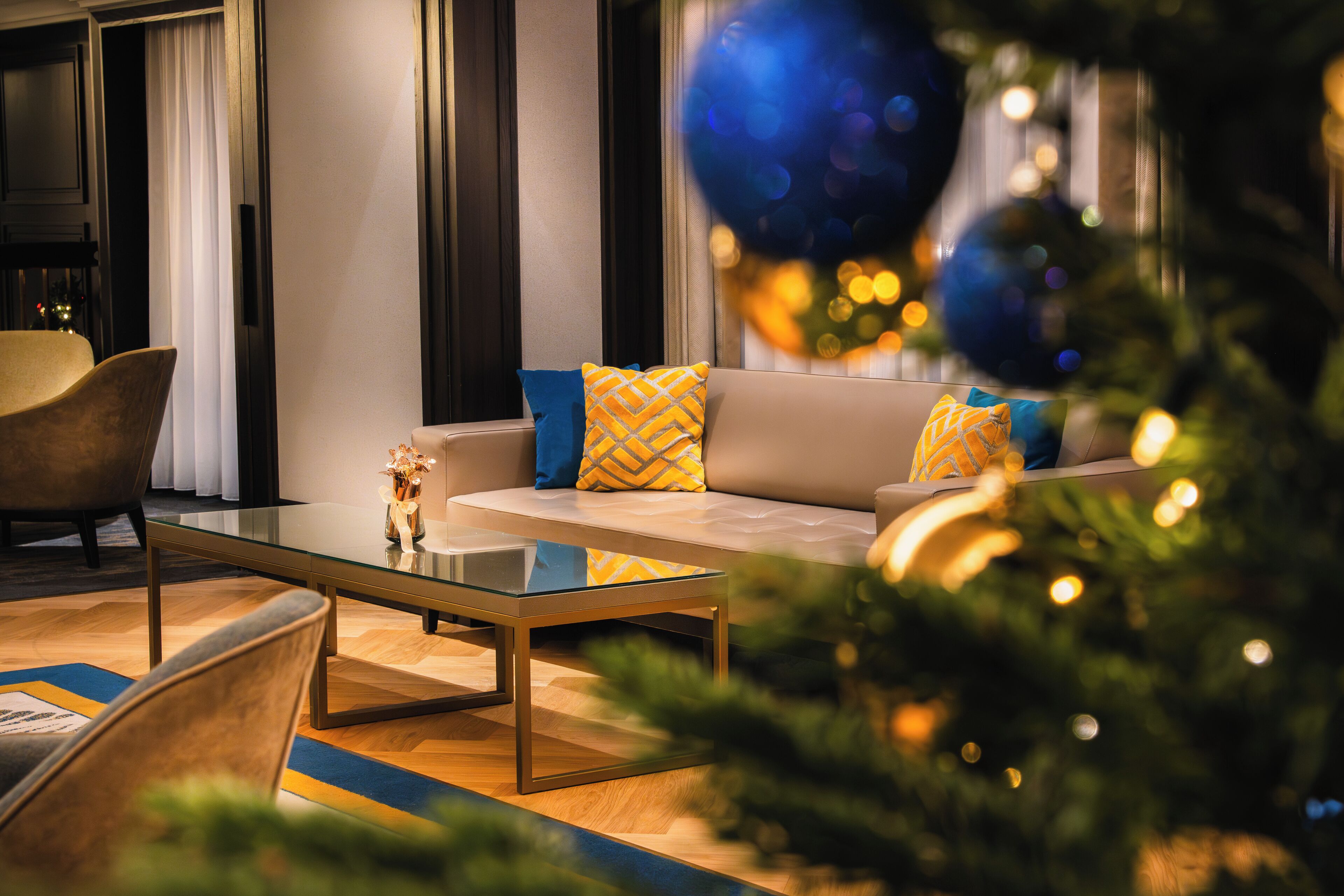 A modern living room with a sofa, armchairs, and a glass coffee table.