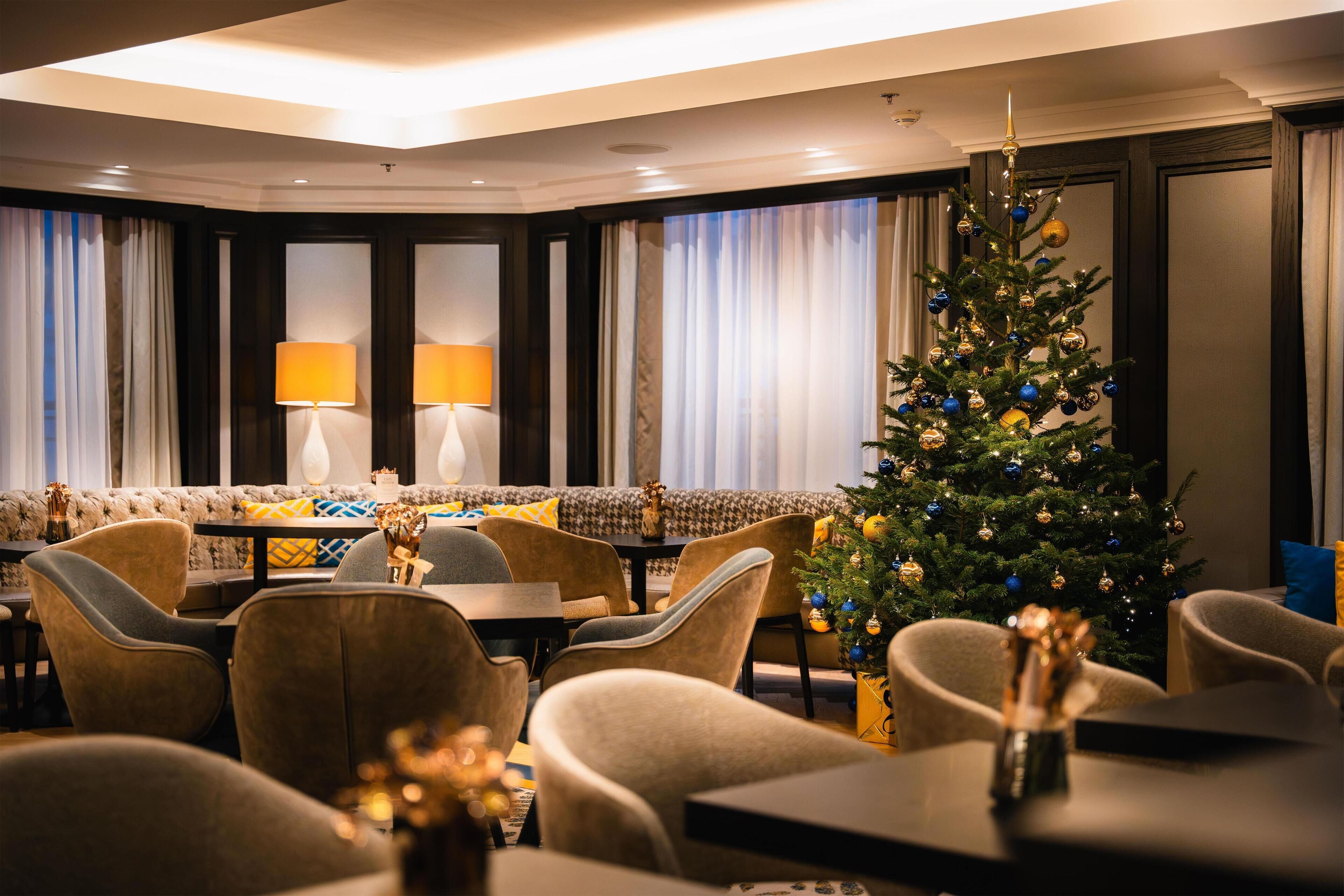 A hotel lobby with a Christmas tree, sofas, and tables.