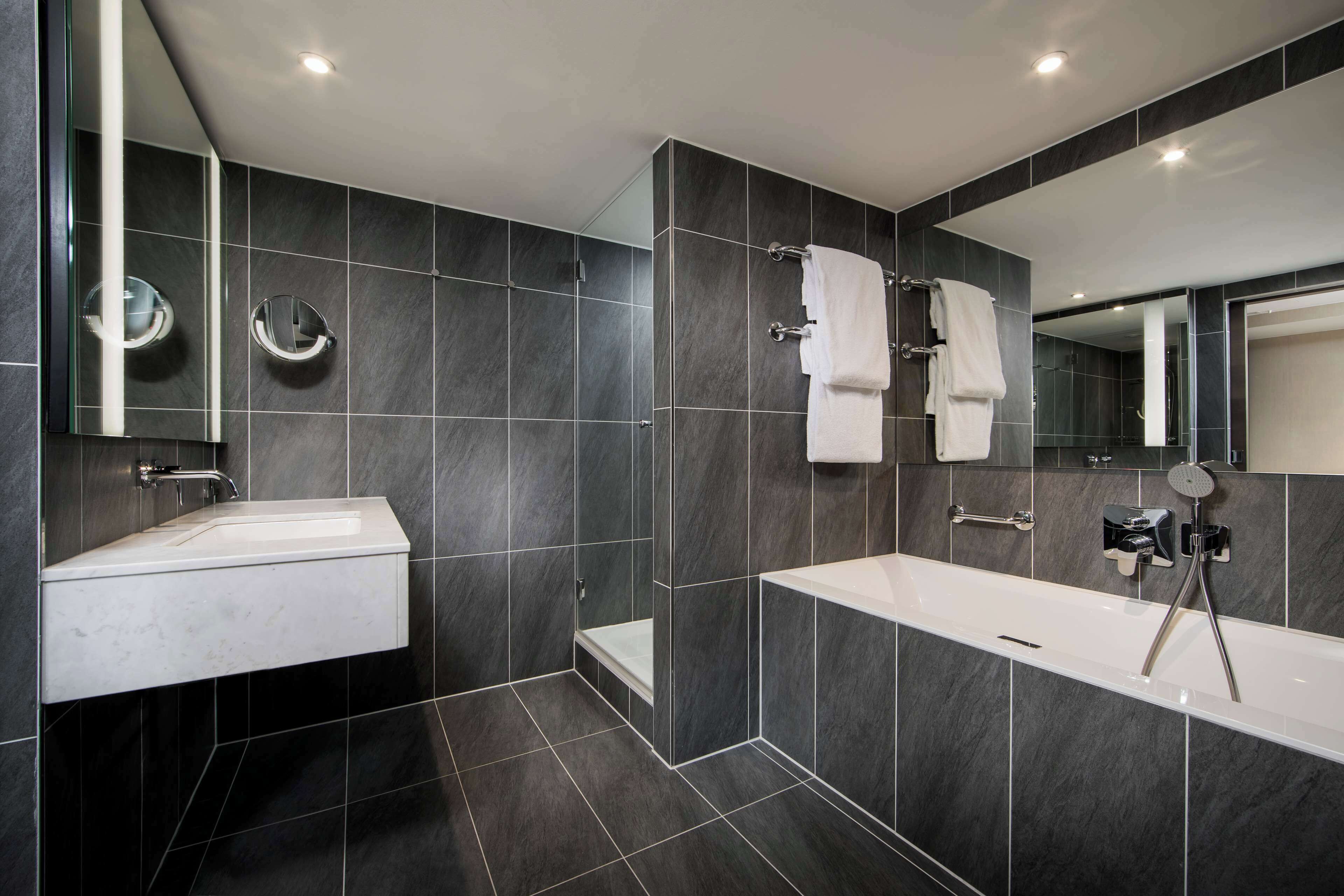 A modern bathroom with a white sink, a bathtub, and a shower area.