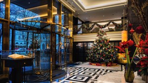 A lobby with a Christmas tree, a piano, and a glass-enclosed area with a view of the street. - Hilton Vienna Plaza (Vienna)