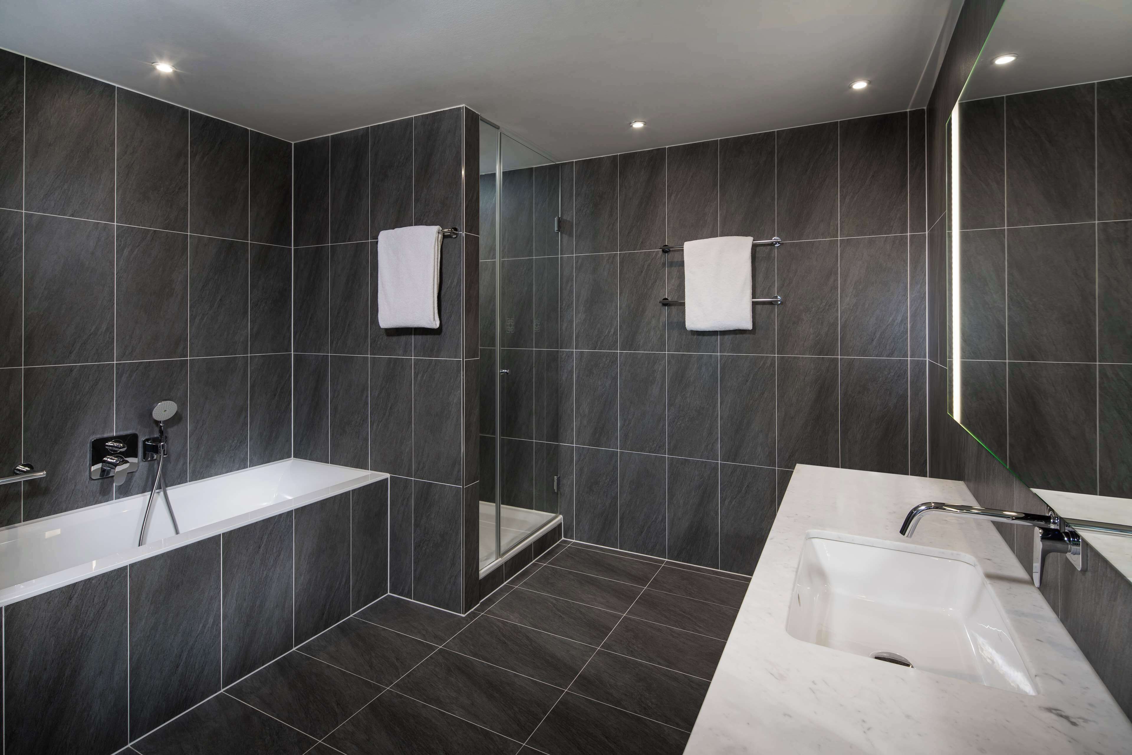 Une salle de bain moderne dotée d’une grande baignoire, d’un espace douche et d’un meuble-lavabo.