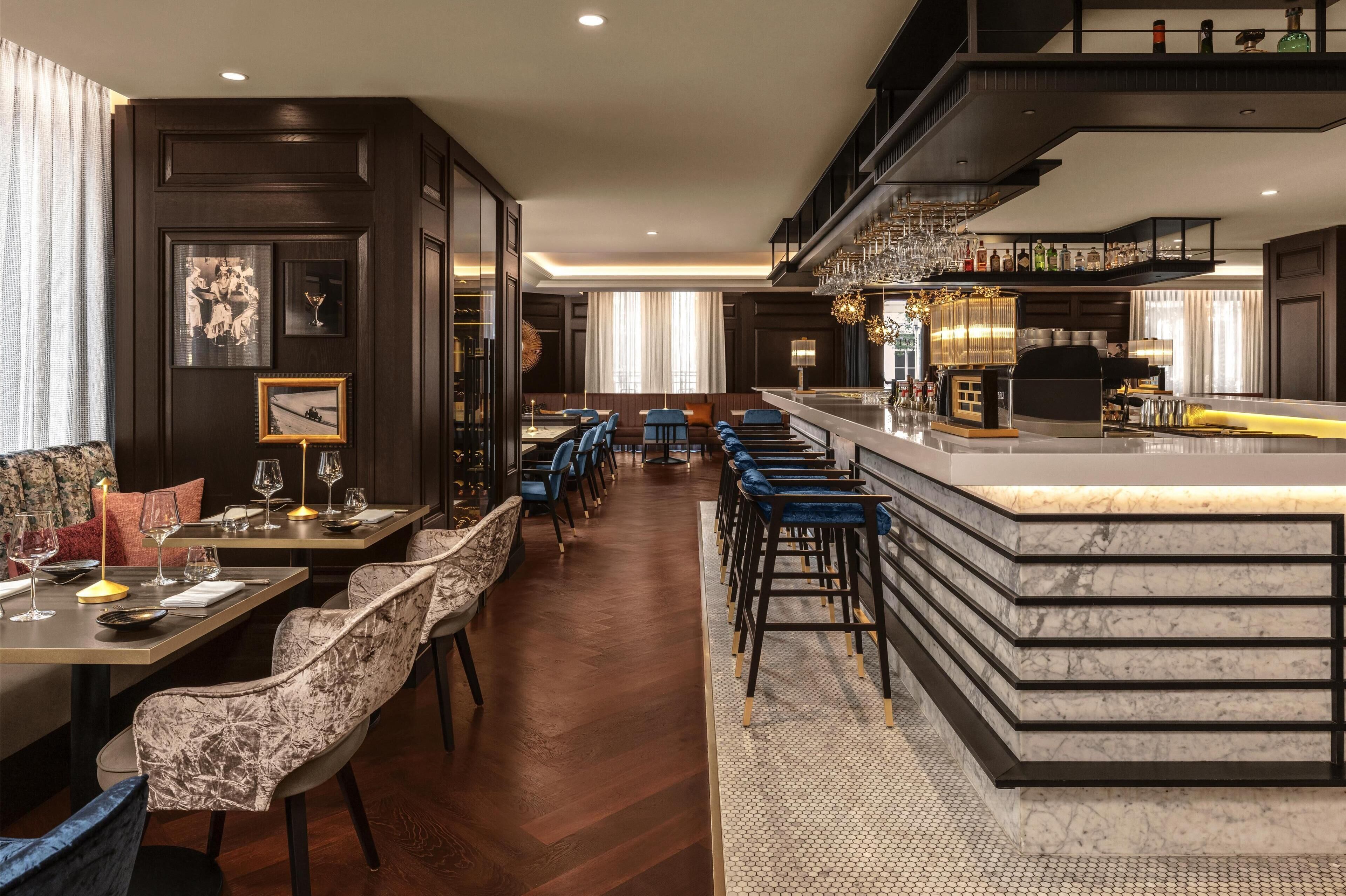 A modern bar area with marble counters and blue bar stools.
