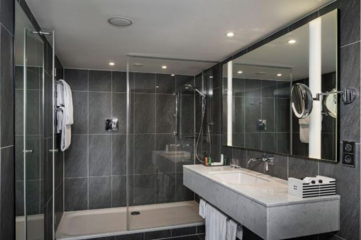A modern bathroom with a glass-enclosed shower, a standalone bathtub, and a vanity with a large mirror.