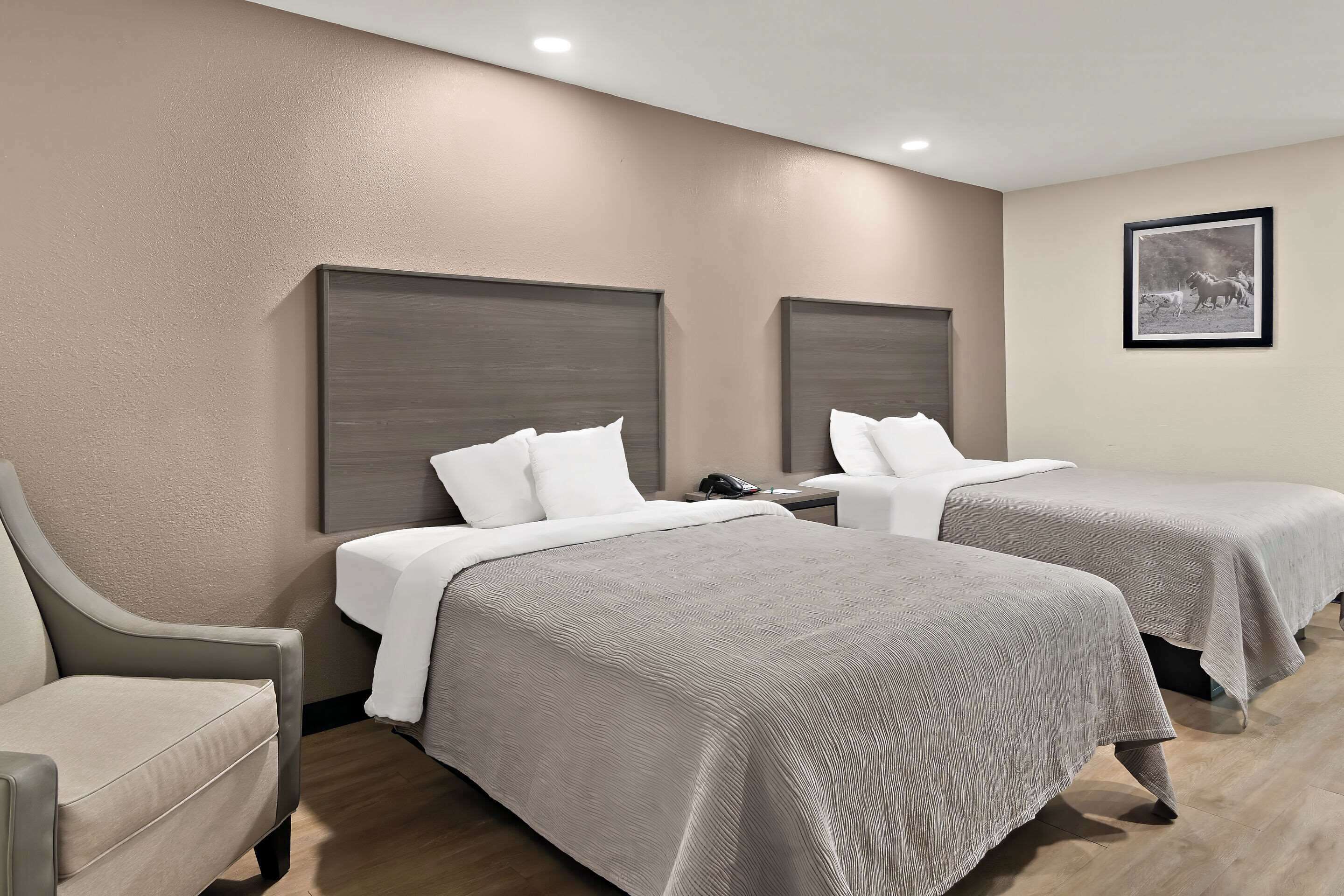 A hotel room with two beds, a sofa, and a framed picture on the wall.