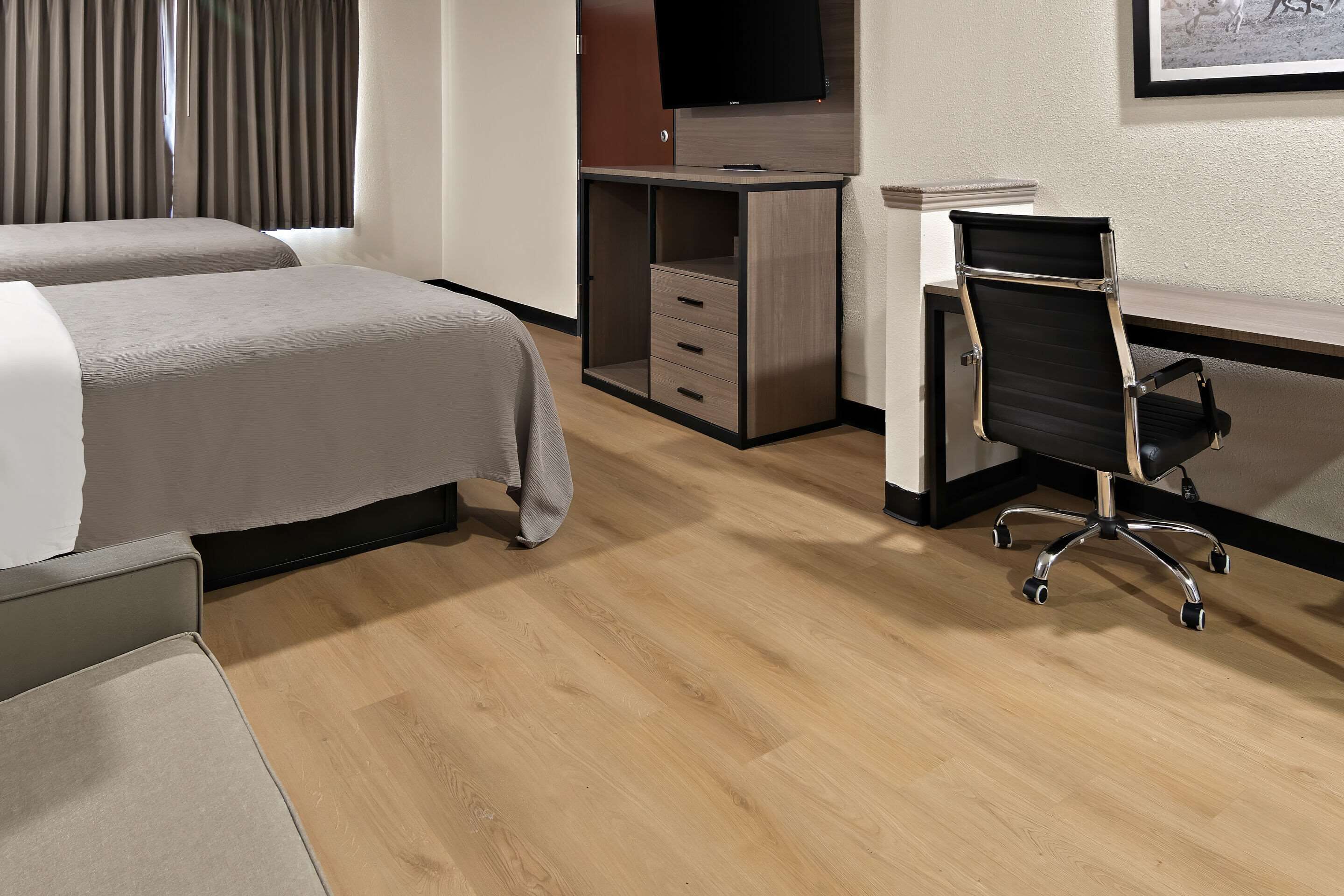 Habitación de hotel con dos camas, un escritorio, una silla y un televisor.
