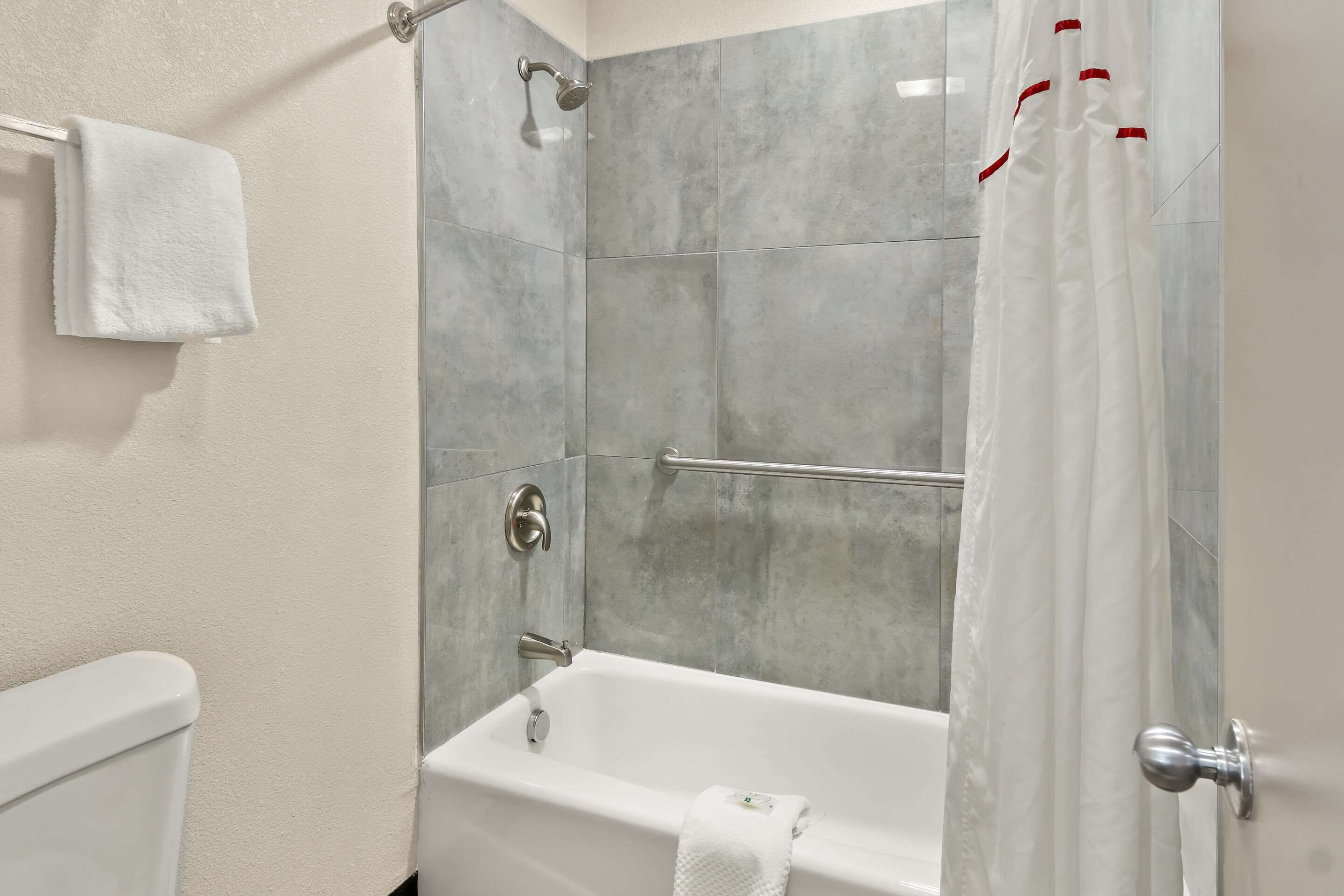 A modern bathroom with a bathtub, a shower curtain, and a towel rack.
