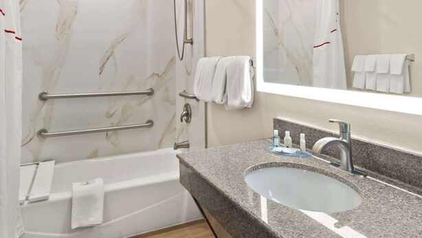 A bathroom with a marble shower wall, a bathtub, a vanity with a sink, and a mirror. - Quality Inn & Suites Weatherford (Weatherford)