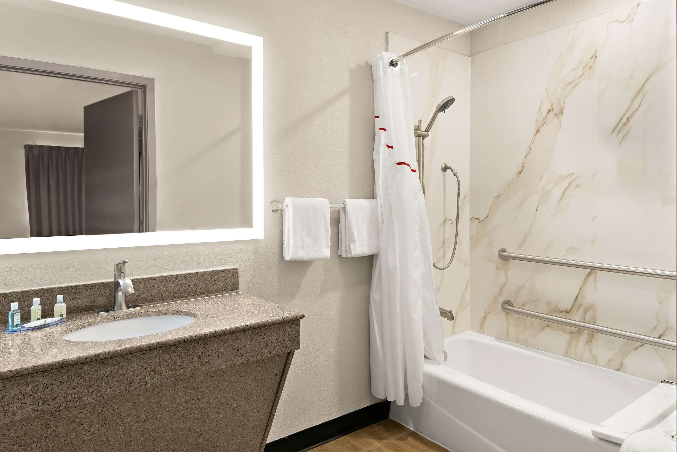 Un baño con lavamanos, espejo, ducha y bañera.