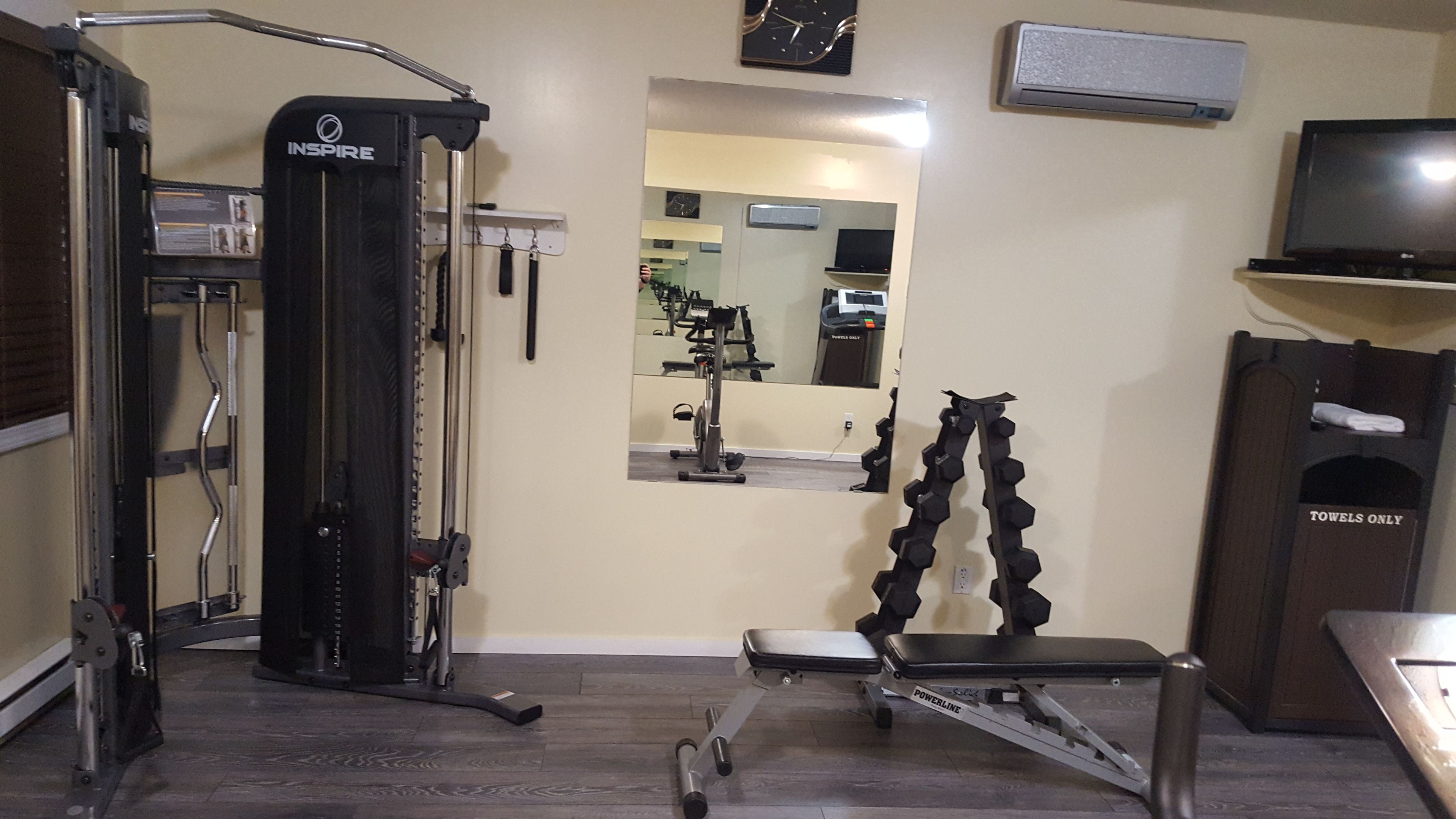 A home gym with a multi-functional exercise machine, a bench, and dumbbells.