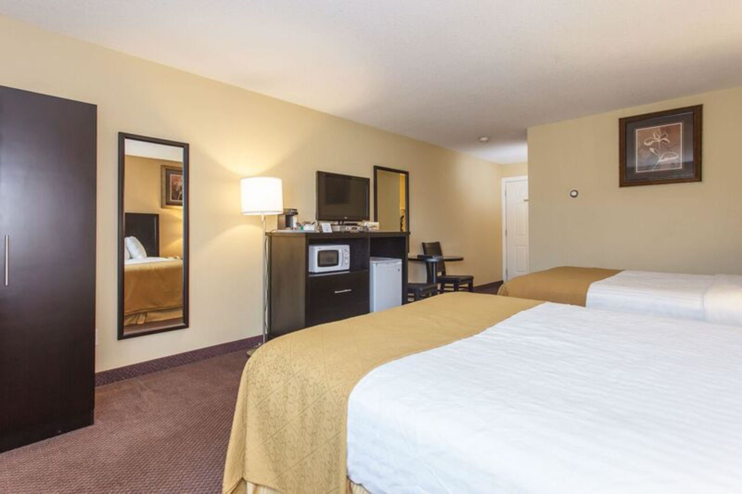 Une chambre d’hôtel équipée d’un lit, d’un bureau avec un ordinateur, d’un four à micro-ondes et d’une télévision.