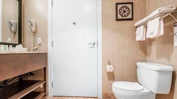 Un baño con inodoro blanco, un lavamanos con espejo y un perchero para toallas.
