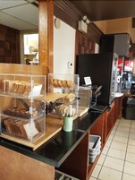 Mostrador de panadería con diversos productos horneados exhibidos en recipientes transparentes.