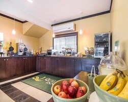 Una cocina con frutero que contiene manzanas y plátanos, un microondas y una cafetera.