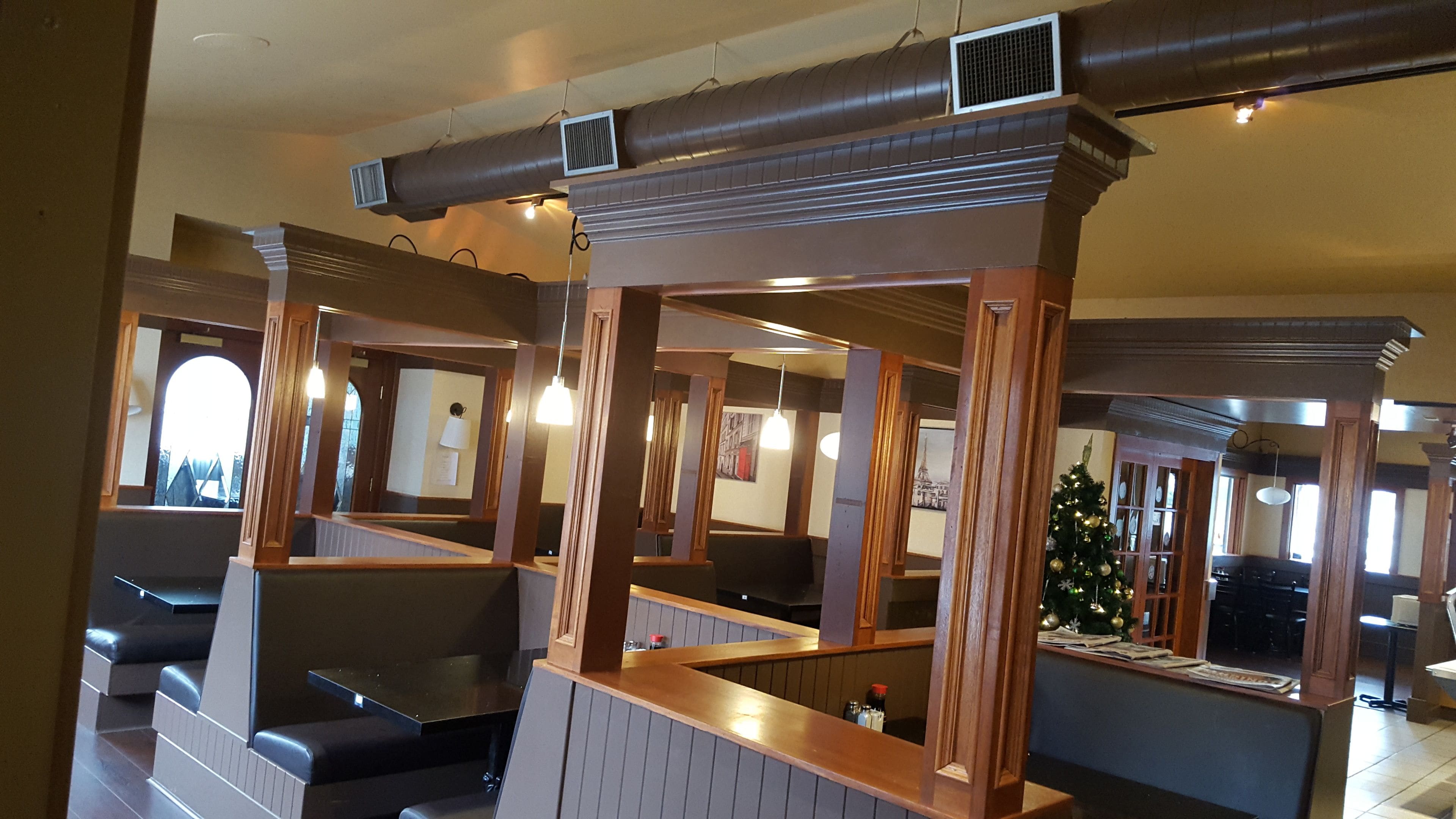 Een restaurant met zitbankjes, houten pilaren en een kerstboom.