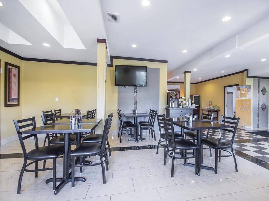 Un restaurante con varias mesas y sillas, un televisor de pantalla plana en la pared y un suelo con estampado de cuadros.