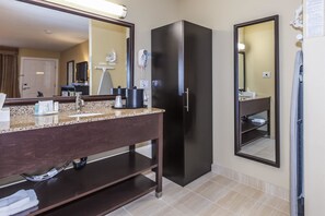 Une salle de bain moderne avec un comptoir en granit, des meubles de couleur sombre, un réfrigérateur noir et un grand miroir.