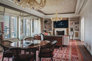 A spacious room with a large window, a fireplace, a television, and a dining area with chairs and a table.