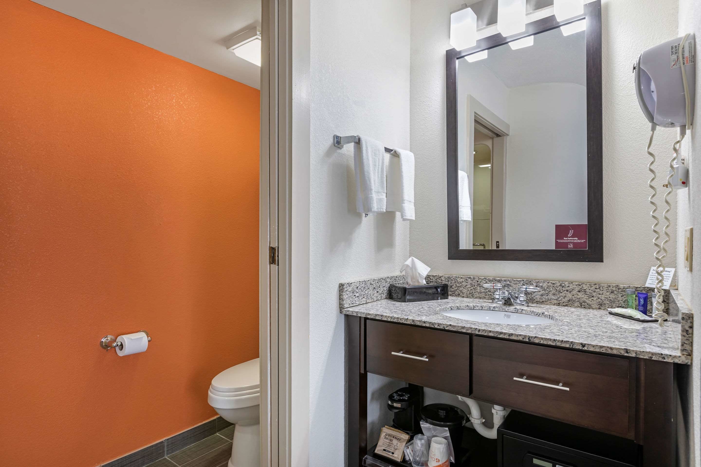 A bathroom with a white toilet, a sink with a mirror above it, and a hairdryer on the wall.
