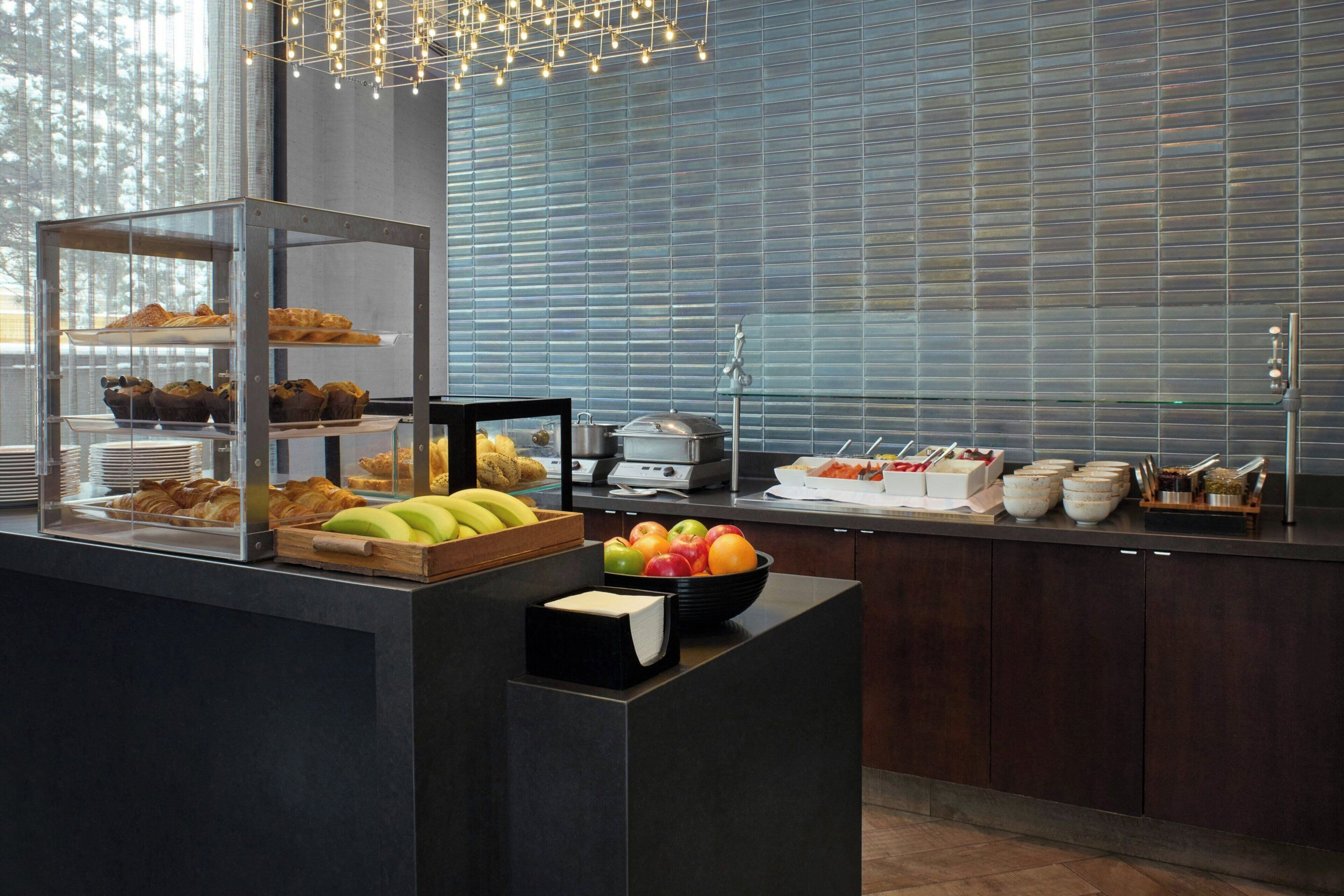 A buffet setup with various food items and a fruit bowl.
