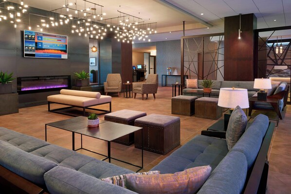 A modern lobby with a fireplace, seating areas, and a digital display. - Toronto Airport Marriott Hotel (Toronto)