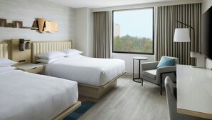 Habitación de hotel con dos camas, un escritorio, una silla, un televisor y una ventana con cortinas.