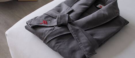 A neatly folded grey robe with a red logo on a white surface.