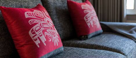 A grey sofa with two red pillows featuring white tribal patterns.
