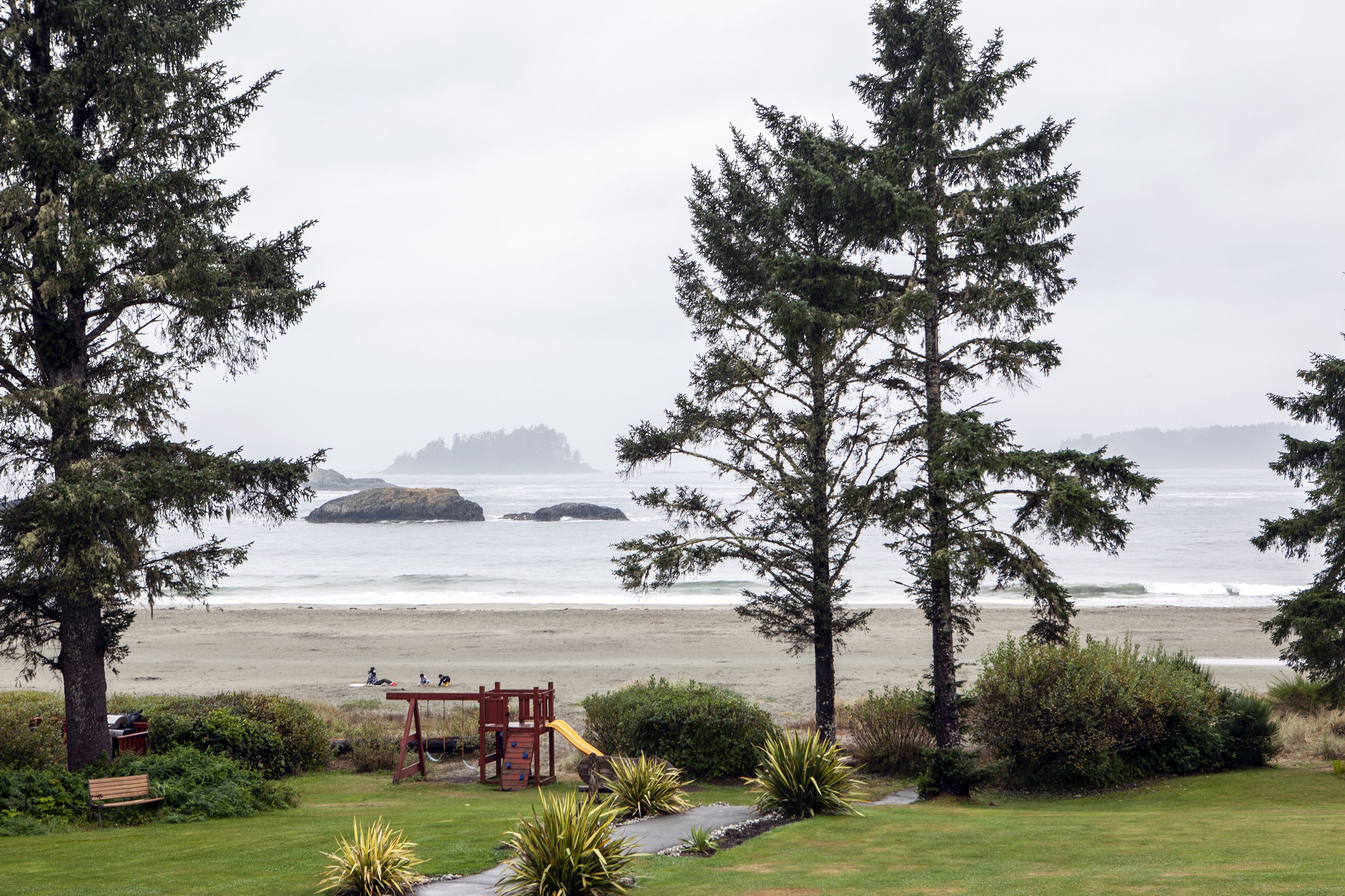A park with a playground, benches, and a view of the ocean.