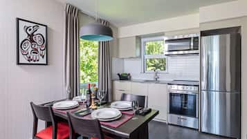 Una cocina moderna con electrodomésticos de acero inoxidable, un comedor con sillas rojas y un ventanal con vistas al verdor.