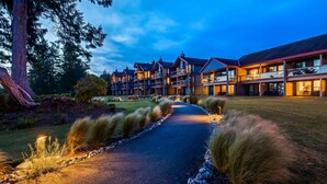 A multi-story hotel with a central courtyard, outdoor seating, and a well-maintained lawn. - Best Western Plus Tin Wis Resort (Tofino)