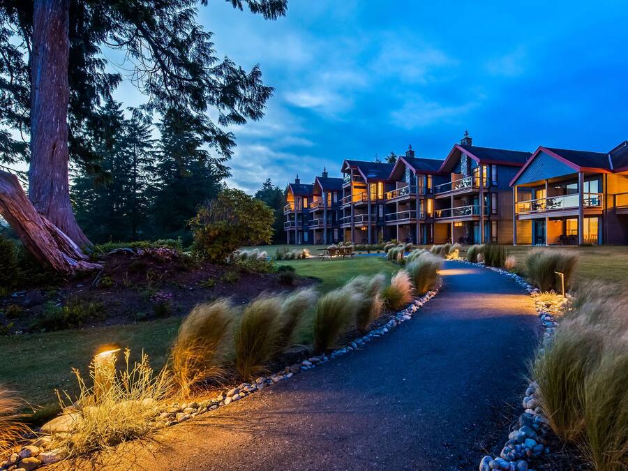 A multi-story hotel with a central courtyard, outdoor seating, and a well-maintained lawn.