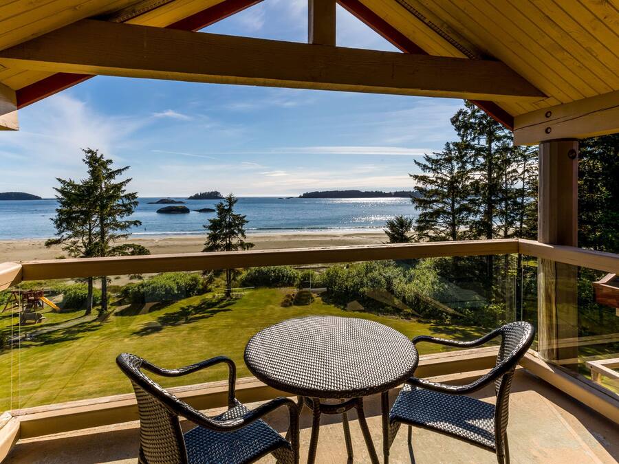 A balcony with a view of the beach and ocean, furnished with a round table and two chairs.