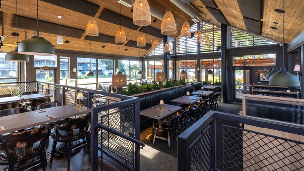 A restaurant with wooden ceiling beams, hanging pendant lights, and a mix of booth and table seating. - Best Western Plus Tin Wis Resort (Tofino)