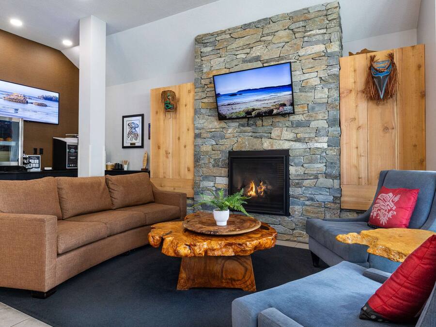 Un salon chaleureux avec une cheminée en pierre, un téléviseur fixé au mur et une table basse en bois.