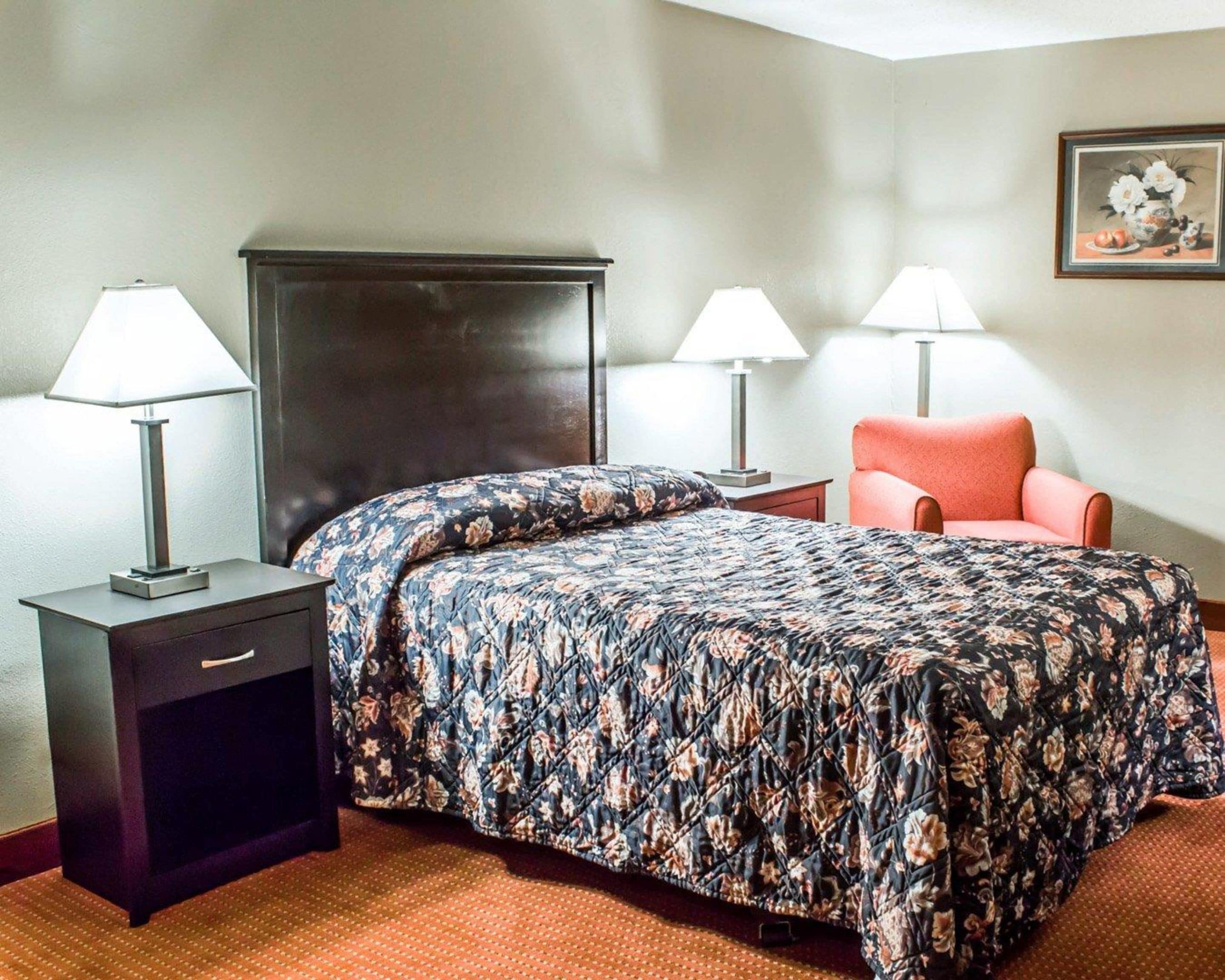 A hotel room with a bed, two bedside tables, a chair, and a nightstand.